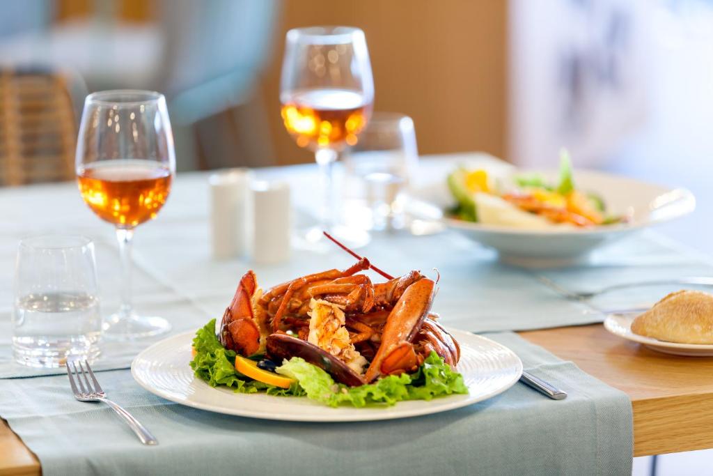 Svaiga jūras velšu plate ar garnelēm un krabjiem, pasniegta uz galda blakus glāzēm ar dzērieniem. Svaigi salāti un maize papildina maltīti.