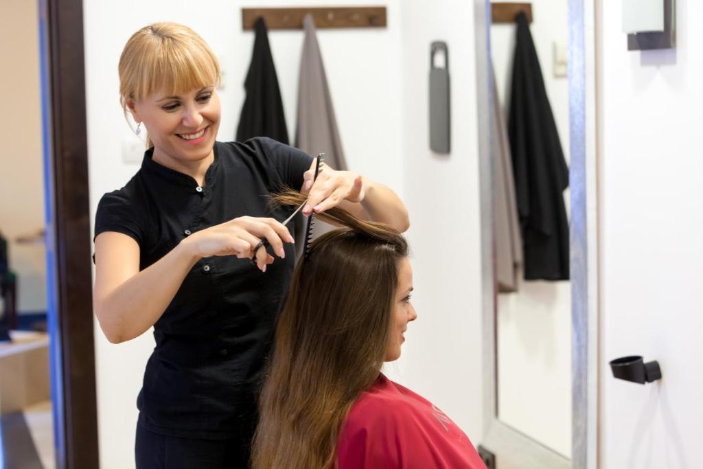 Frizieris griež matu, kamēr klients sēž krēslā. Frizētava ir gaiša un moderna, ar spoguli un matu apstrādes rīkiem.