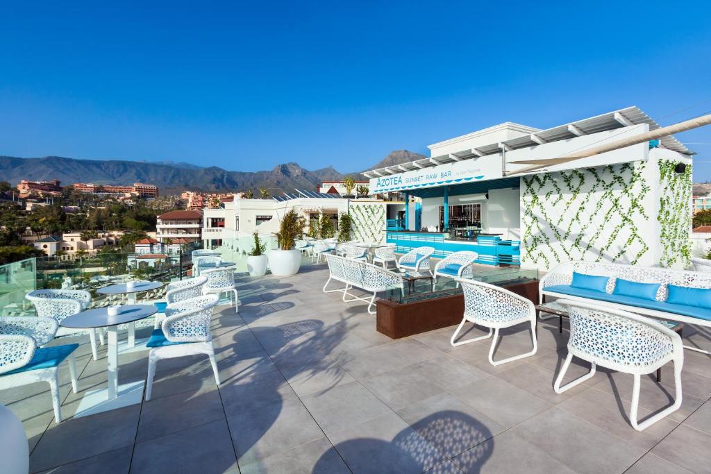 Moderns jumta bārs ar baltām mēbelēm un zilo akcentu, piedāvā skatu uz kalniem un pilsētas ainavu. Ideāla vieta relaksācijai un saulrieta baudīšanai.