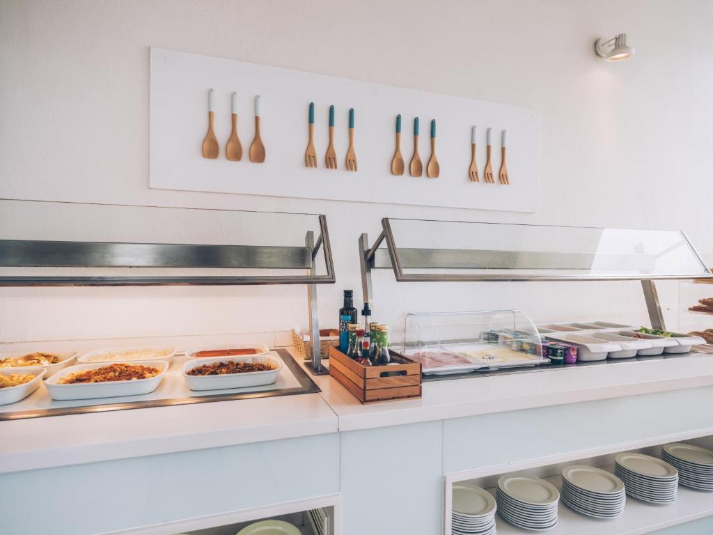 Brokastu bufete ar dažādiem ēdieniem, stilīgu trauku un koka karotēm, kas rotā sienu. Eleganta un moderna uzkodu stacija.