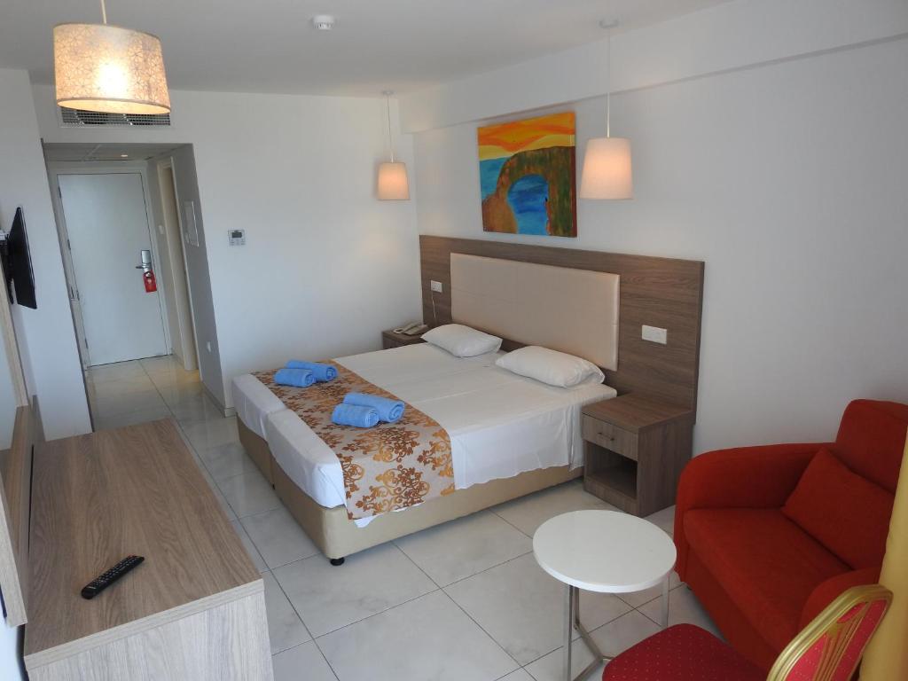 Mūsdienīgs viesnīcas numurs ar divām gultām, dīvānu un galdiņu, papildināts ar gaismu un krāsainu mākslas darbu uz sienas. Numurs ir gaišs un ērts, ideāli piemērots atpūtai.