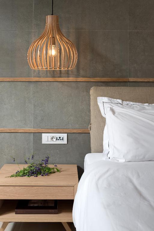 Moderns guļamistabas interjers ar koka lampu, mīkstu gultu un elegantu naktsgaldiņu, uz kura atrodas zaļumi.