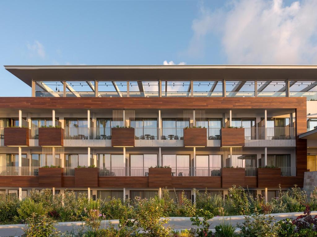 Mūsdienīgs viesnīcas komplekss ar koka apdari un balkoniem, kas apzaļumoti ar augiem. Apkārt ir ziedi un krūmi, radot relaksējošu atmosfēru.