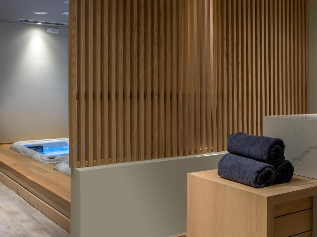 Mūsdienīgs spa interjers ar koka slīpētiem paneļiem, kur blakus atrodas sakārtotas dvieļi un burbuļvanna. Ideāla vieta relaksācijai un atpūtai.