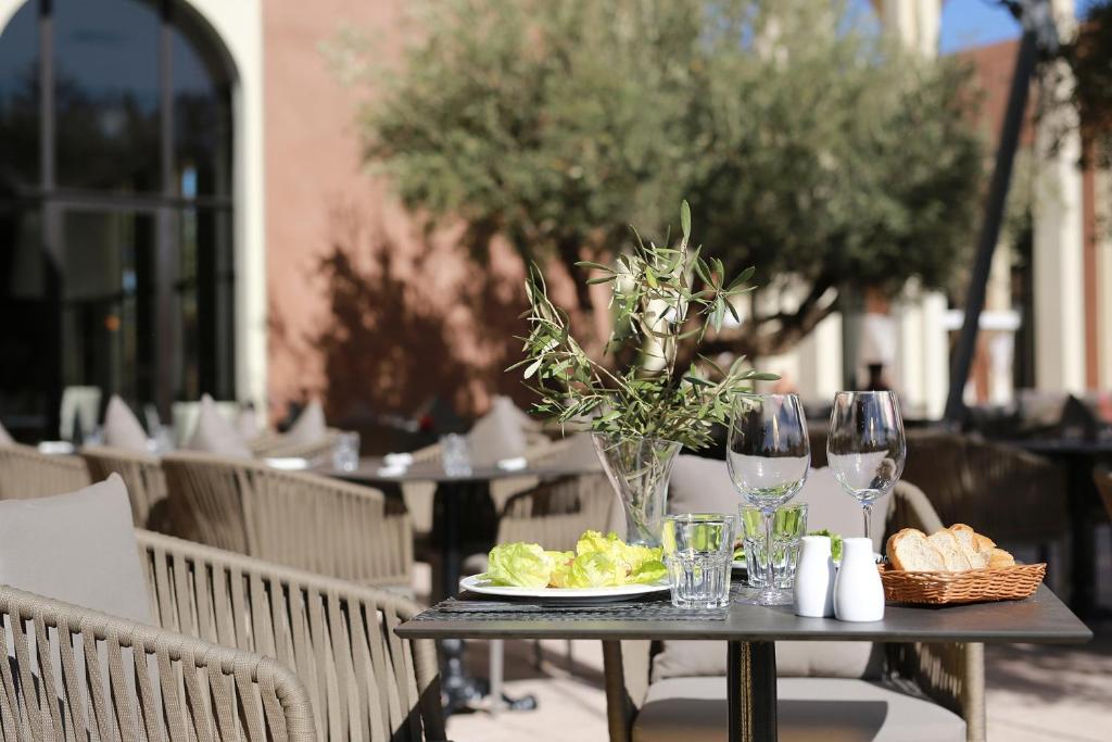 Āra restorāna galdiņš ar brīnišķīgu skatu, uz kura atrodas salātu šķīvis, dzērienu glāzes, sāls un piparu trauki, kā arī maize groziņā.