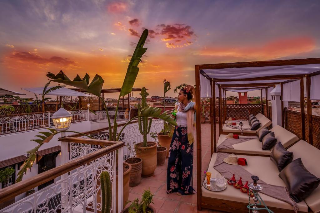 Saulrieta skats no jumta terases ar cilvēku, kas izbauda atmosfēru, apkārt ir augi un eleganti guļamkrēsli. Dabas krāsas un relaksējoša vide rada mierīgu noskaņu.