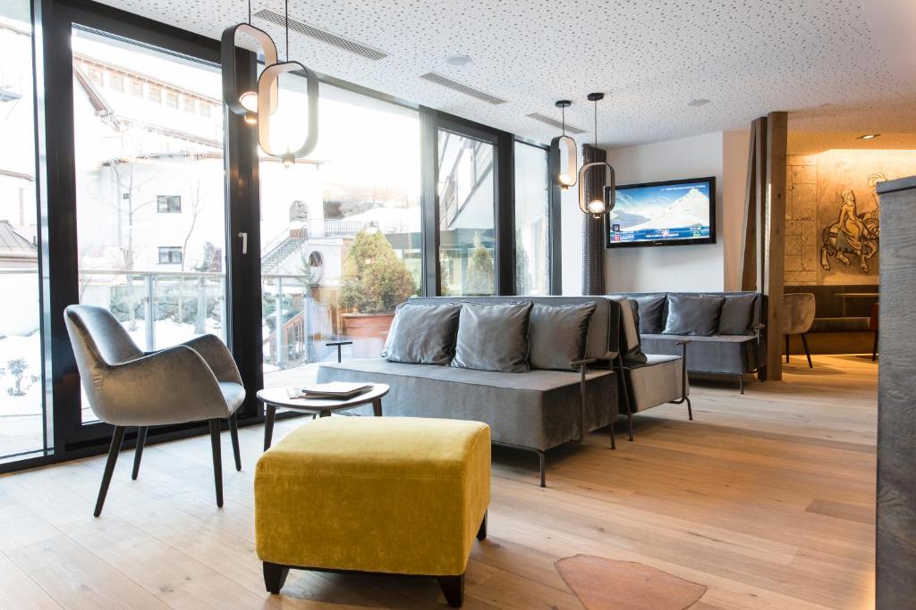 Mūsdienīgs viesnīcas interjers ar ērtām mēbelēm un lieliem logiem, kas sniedz skatu uz ārpusi. Gaismas elementi papildina telpas estētiku.