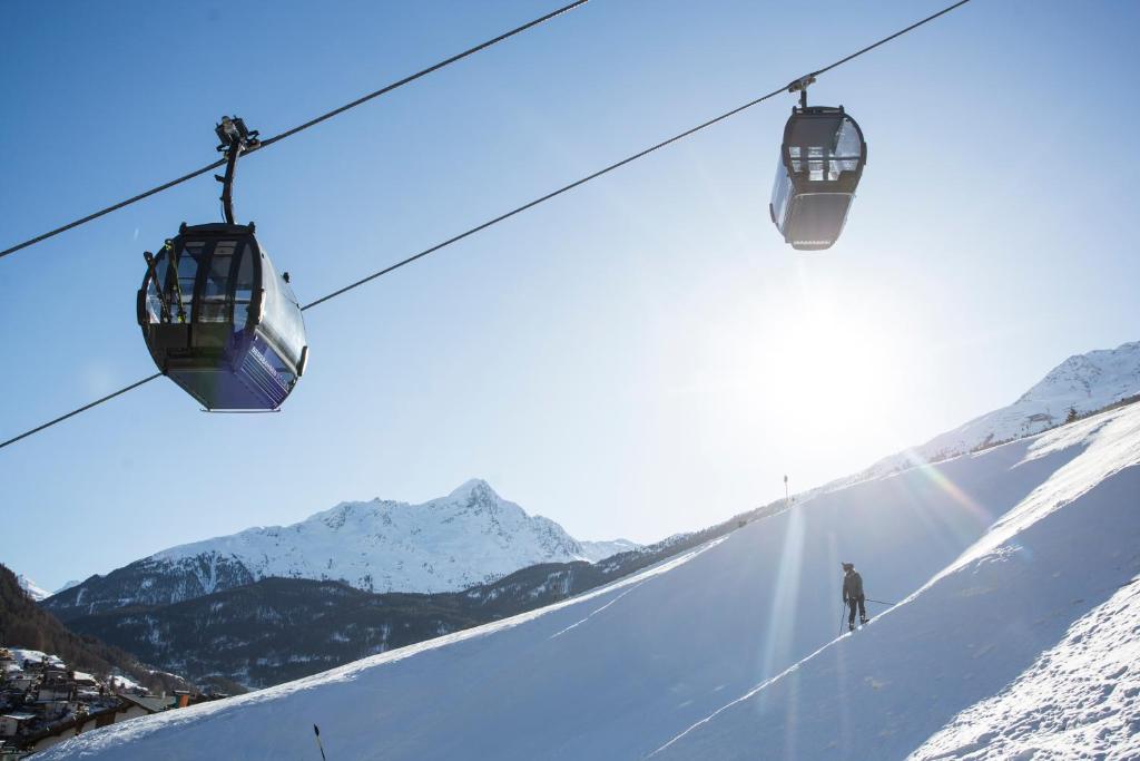 Slēpošanas pacēlāji virs sniegotām kalnu nogāzēm, saulains laiks un skaidrs debesis. Ideāla ziemas brīvdienu aina.