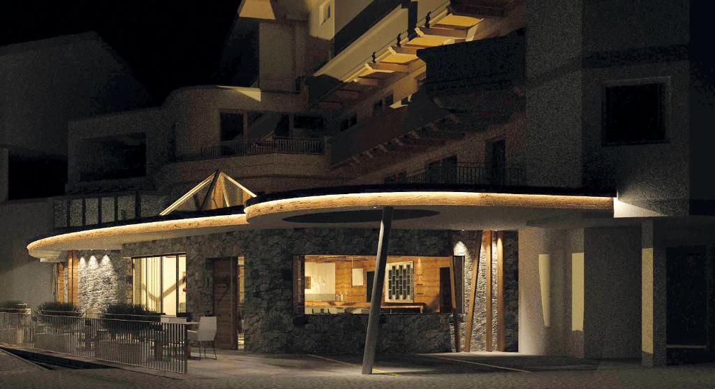 Mūsdienīga arhitektūra, kas izceļas ar akmens fasādi un izsmalcinātu apgaismojumu naktī. Eleganta un pārdomāta ēkas forma pievērš uzmanību.