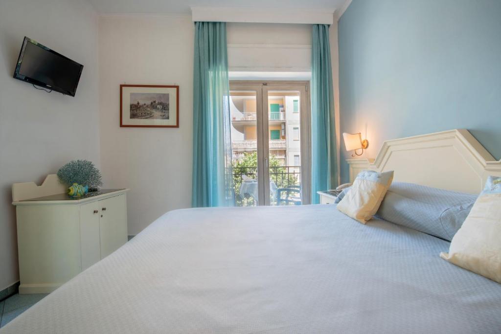 Gaiša viesnīcas istaba ar plašu gultu, televizoru, krāšņu skatu pa logu un vieglām aizkariem. Interjerā ir izmantoti mierīgi toņi un dekoratīvi elementi, kas rada relaksējošu atmosfēru.