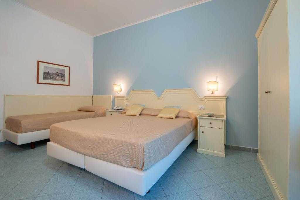 Gaišs viesnīcas numurs ar divām gultām, gaiši zilu sienu un mēbelēm, kas nodrošina komfortablu un relaksējošu atmosfēru. Numurā ir naktsgaldiņš un mēbeļu skapītis.