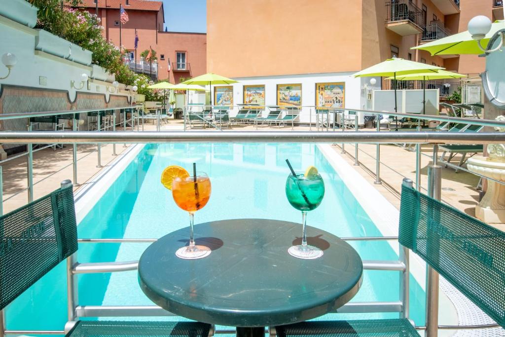 Baseins ar divām krāsainām kokteiļu glāzēm, zaļiem saulessargiem un atpūtas krēsliem. Ideāla atpūtas vieta vasaras dienām.
