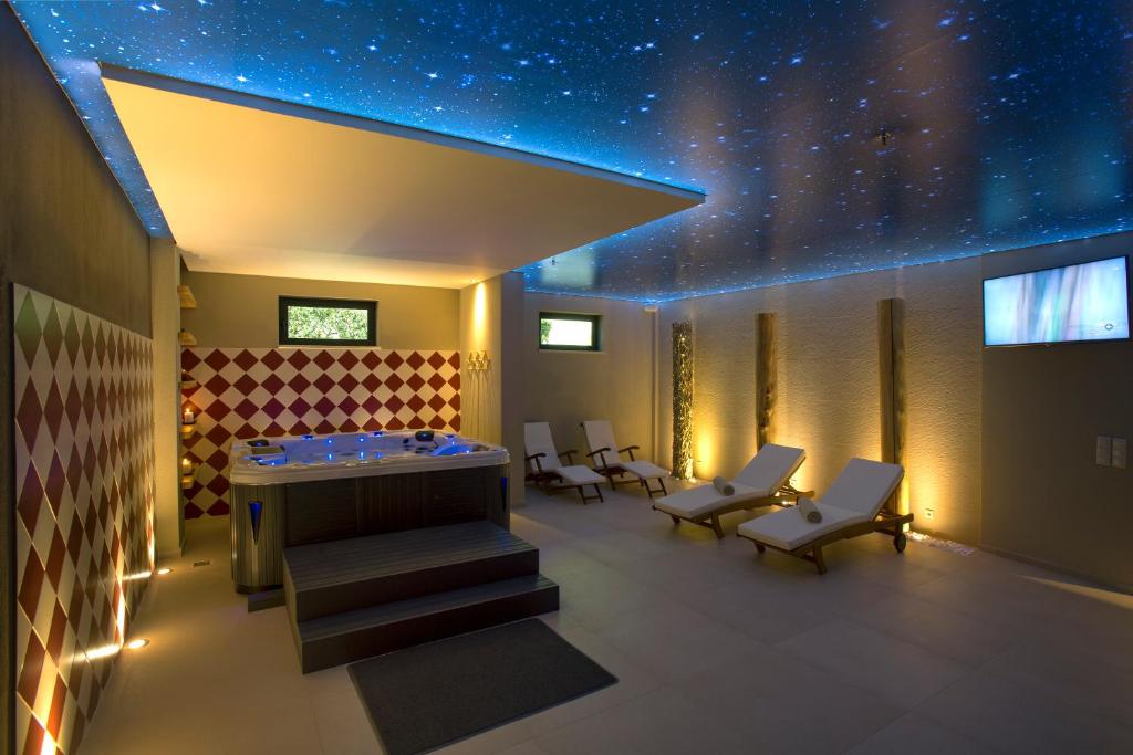 Mūsdienīgs spa interjers ar burbuļvannu, atpūtas krēsliem un zvaigžņotām griestiem, nodrošinot relaksējošu atmosfēru. Apgaismojums rada mierīgu noskaņu, ideāli piemērots atpūtai.