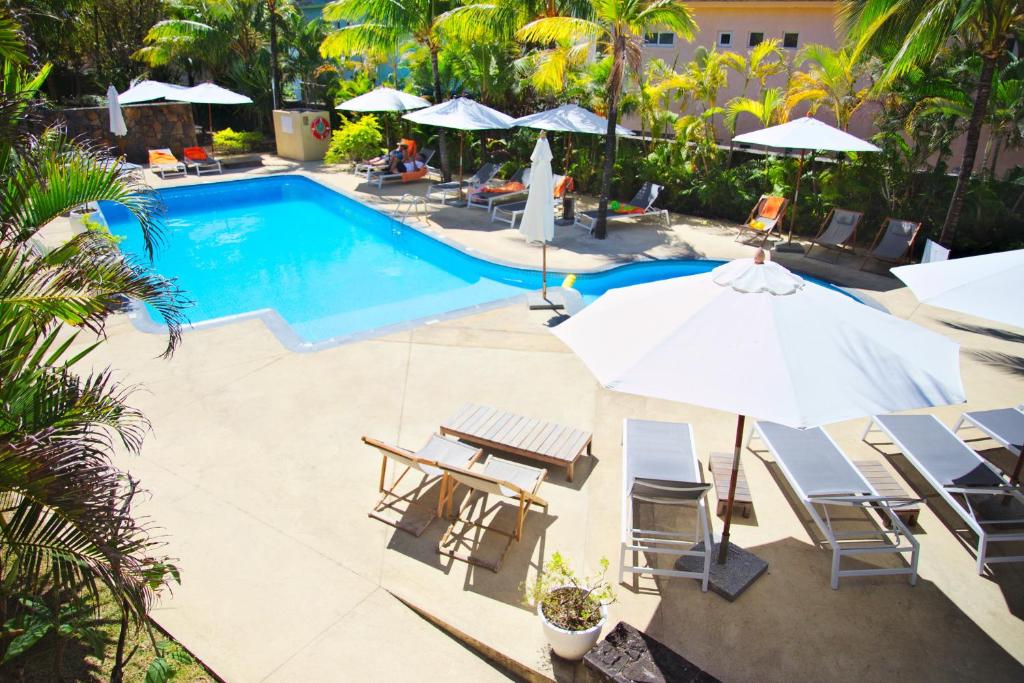 Baseins ar zilo ūdeni un saulessargiem, ieskauts ar palmām un atpūtas krēsliem. Ideāla vieta relaksācijai un vasaras baudīšanai.