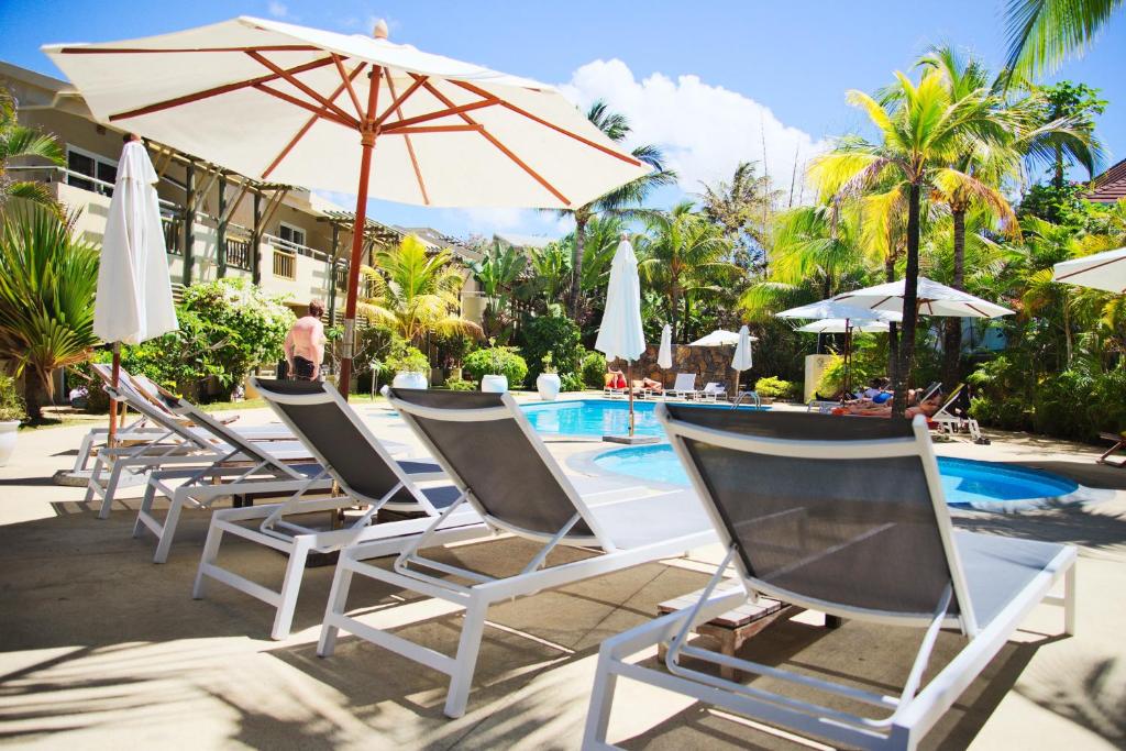 Baseins ar sauļošanās krēsliem un lietussargiem, apkārt augļu palmas un viesnīcas ēka. Ideāla vieta relaksācijai un atpūtai.