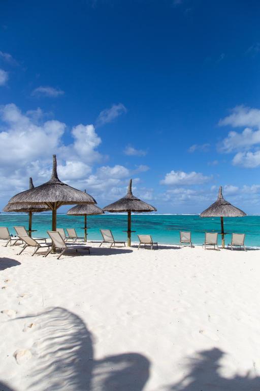 Pludmale ar saules krēsliem un lietussargiem, skats uz tīru, zilu ūdeni un skaidru debesi. Ideāla vieta atpūtai un relaksācijai.