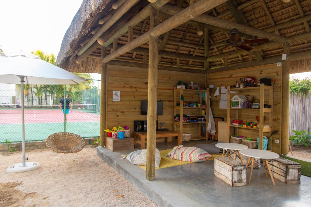 Atpūtas telpa ar dabīgiem materiāliem, kas ietver sēdvietas un plauktus, blakus tenisa laukumiem. Telpa ir gaiša un draudzīga, ar siltu atmosfēru.