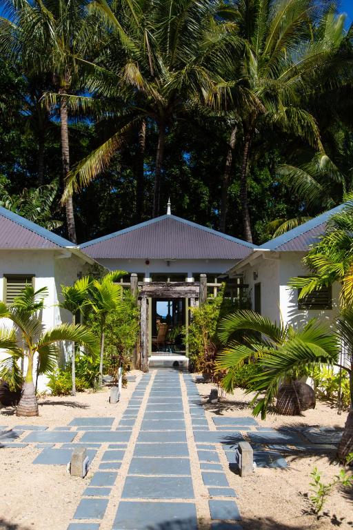 Tropu mājas ieeja ar akmens celiņu un palmu kokiem, kas rada relaksējošu atmosfēru. Ideāls vieta atpūtai un dabas baudīšanai.