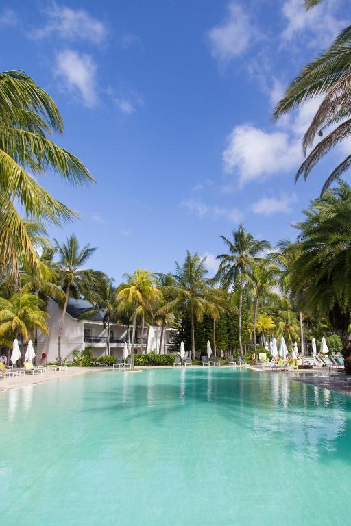 Skaists tropu baseins ieskauts palmām, ar skaidru zilu debesu fonu. Ideāla vieta relaksācijai un atpūtai.