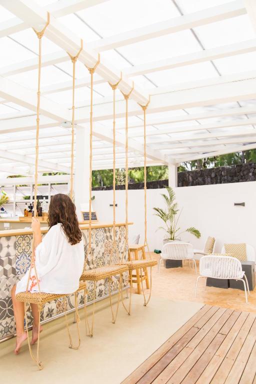 Mūsdienīgs atpūtas stūrītis ar šūpolēm, kas piestiprinātas pie bāra, izceļot relaksējošu atmosfēru. Interjers ir gaišs un viesmīlīgs, ar dabīgām materiālu krāsām un augu elementiem.