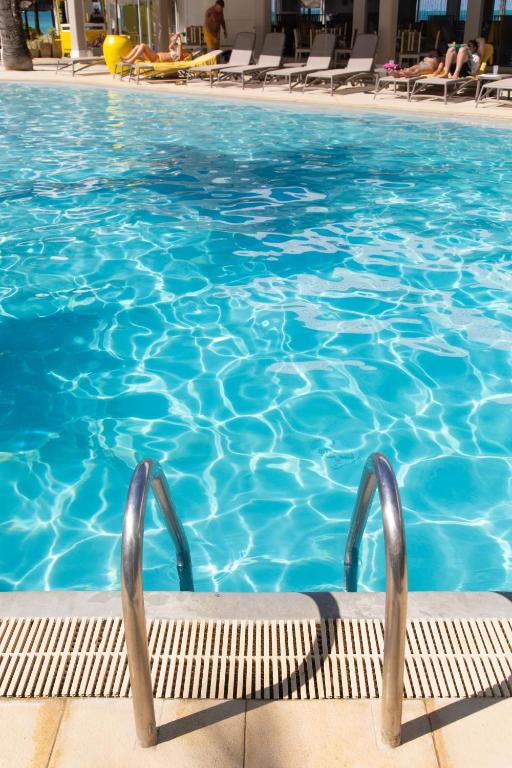 Skaista peldbaseina skats ar sudraba margām un dzidru zilu ūdeni, ap kuru ir saulainas atpūtas zonas. Ideāla vieta relaksācijai un atpūtai.