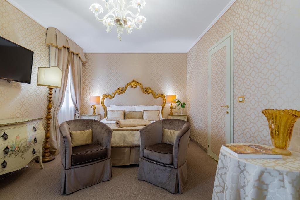 Eleganta viesnīcas numuriņa interjers ar greznu gultu, mīkstiem krēsliem un mūsdienīgu apgaismojumu. Sienas rotā maiga krāsa un dekoratīvi elementi, radot mājīgu atmosfēru.