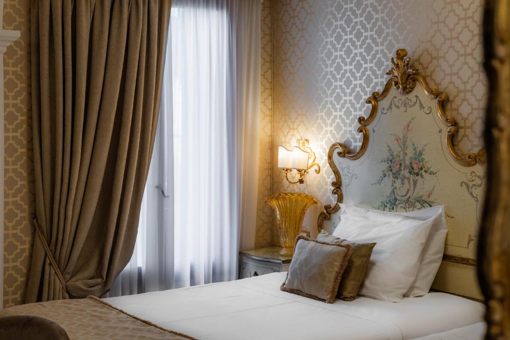 Elegantā guļamistaba ar greznu gultu un mīkstiem aizkariem, kas ieplūst gaismā. Sienas rotā izsmalcināta tapete un grezns naktsgaismas ķermenis.