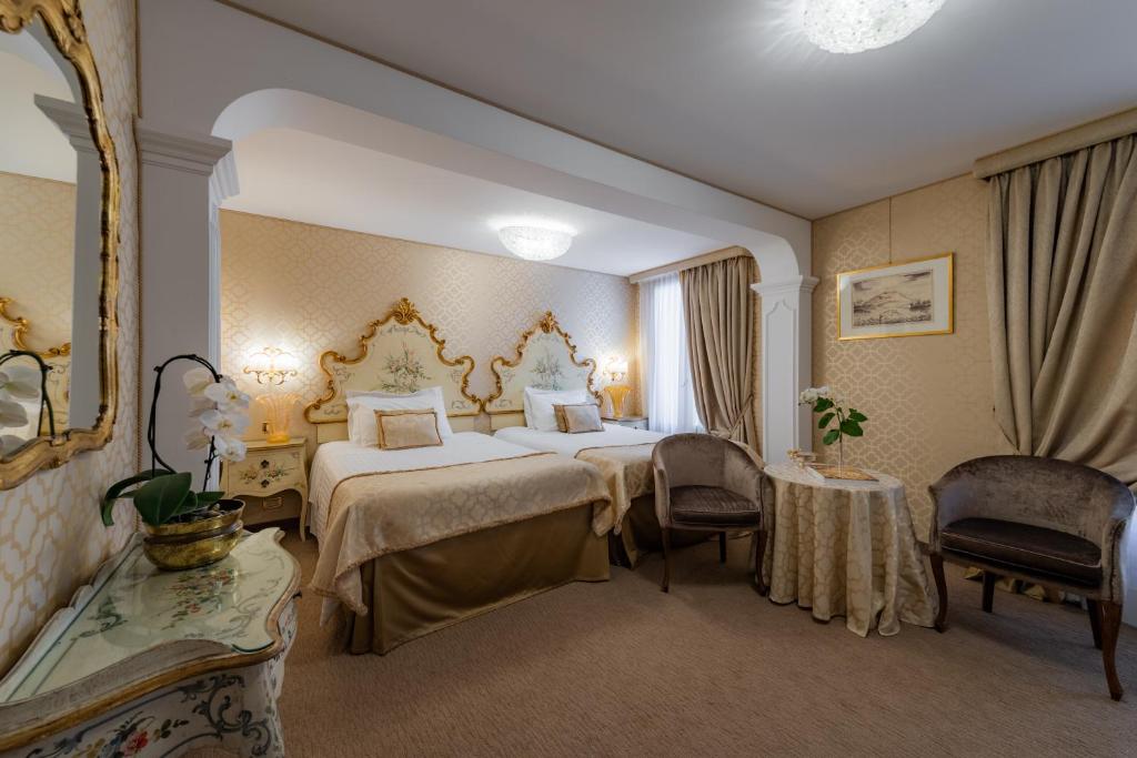 Elegants viesnīcas numurs ar divām gultām, dekorēts ar greznām mēbelēm un mīkstiem toņiem. Telpā ir liels logs, kas nodrošina dabisko apgaismojumu, kā arī raksturs un ziedi uz galda.