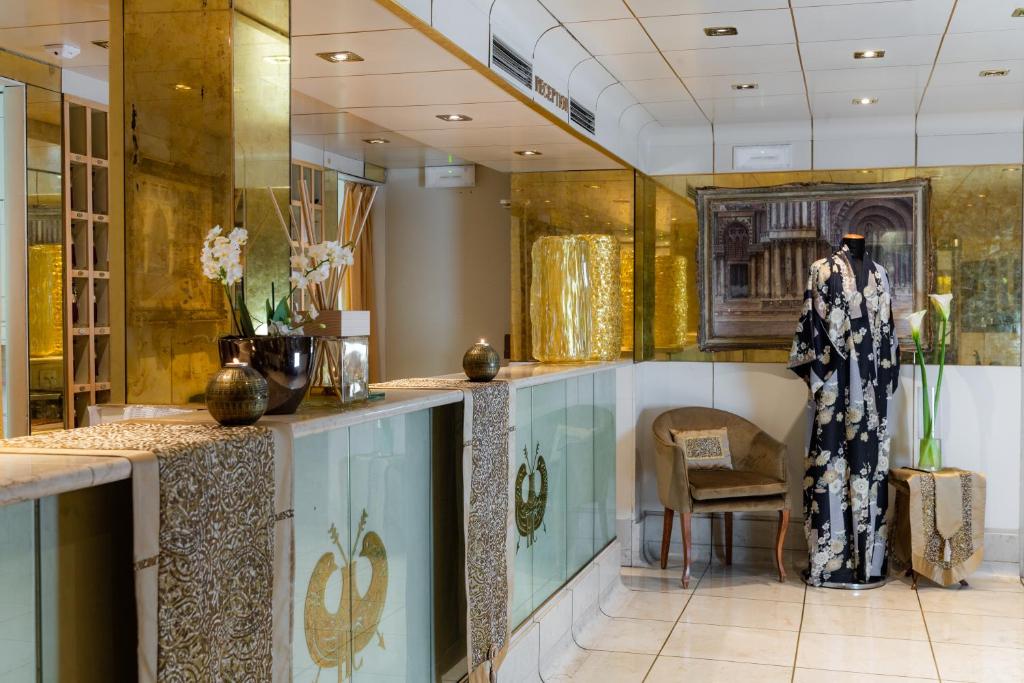 Elegants spa uztveršanas reģistratūras interjers ar zeltainiem akcentiem un tradicionālu kimono. Galda dekorācija ar ziediem un māksliniecisku apgaismojumu rada relaksējošu atmosfēru.