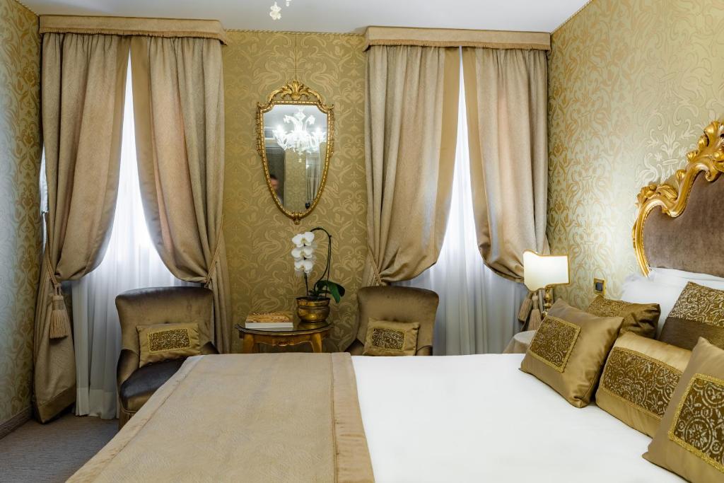 Eleganta guļamistaba ar zeltītiem elementiem, greznam dīvānam un logiem ar smalkām aizkariem. Interjers apvieno mūsdienīgu komfortu ar klasisku stilu.
