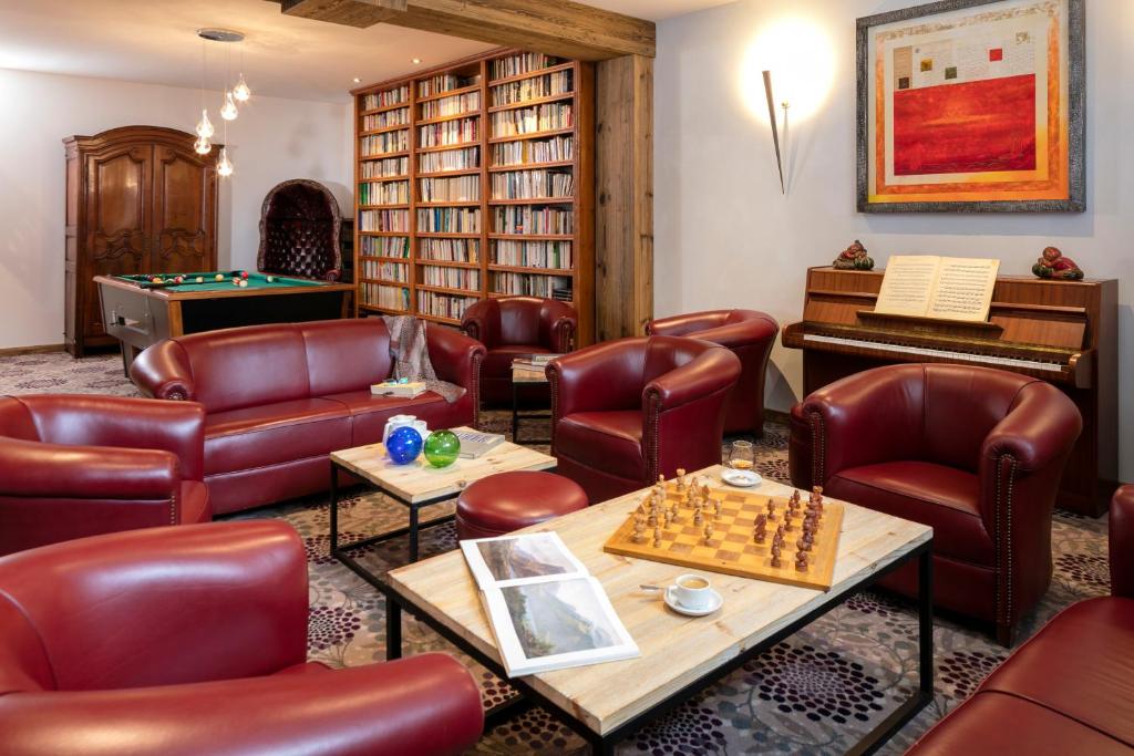 Mūsdienīga atpūtas telpa ar sarkanu ādas mēbeļu komplektu, grāmatu plauktu un šaha galdu. Telpā ir arī biljarda galds un klavieres, radot mājīgu un relaksējošu atmosfēru.