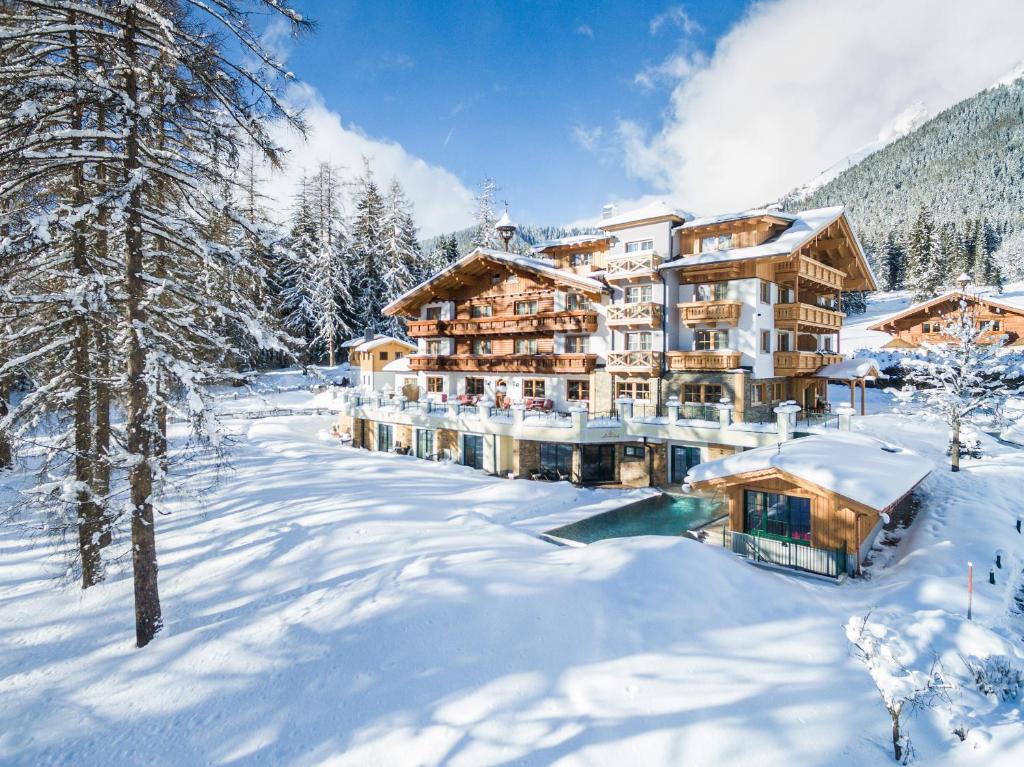 Ziemas ainava ar viesnīcu kalnu rajonā, kur sniegs klāj zemi un kokus. Viesnīca ar tradicionālu arhitektūru ir apņemta ar skaistu dabu.