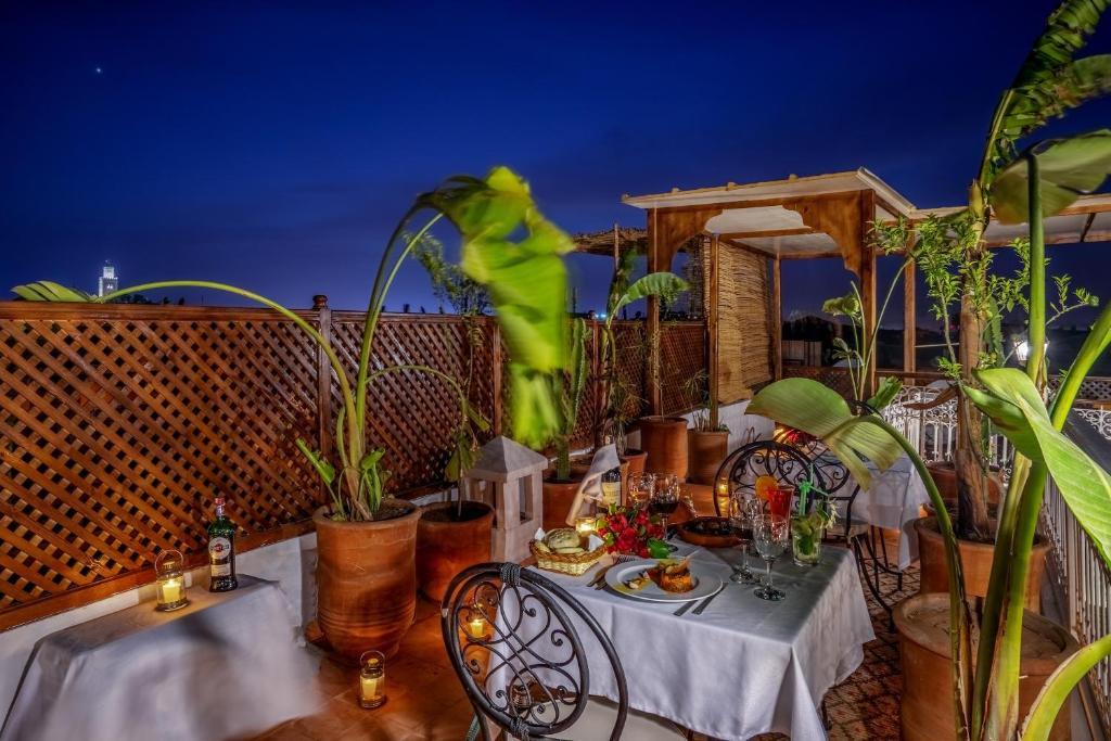 Romantisks terases vakariņu iestatījums ar zaļām augu rotājumiem un skaistu skatu, kas izgaismots ar svecēm un gardiem ēdieniem.