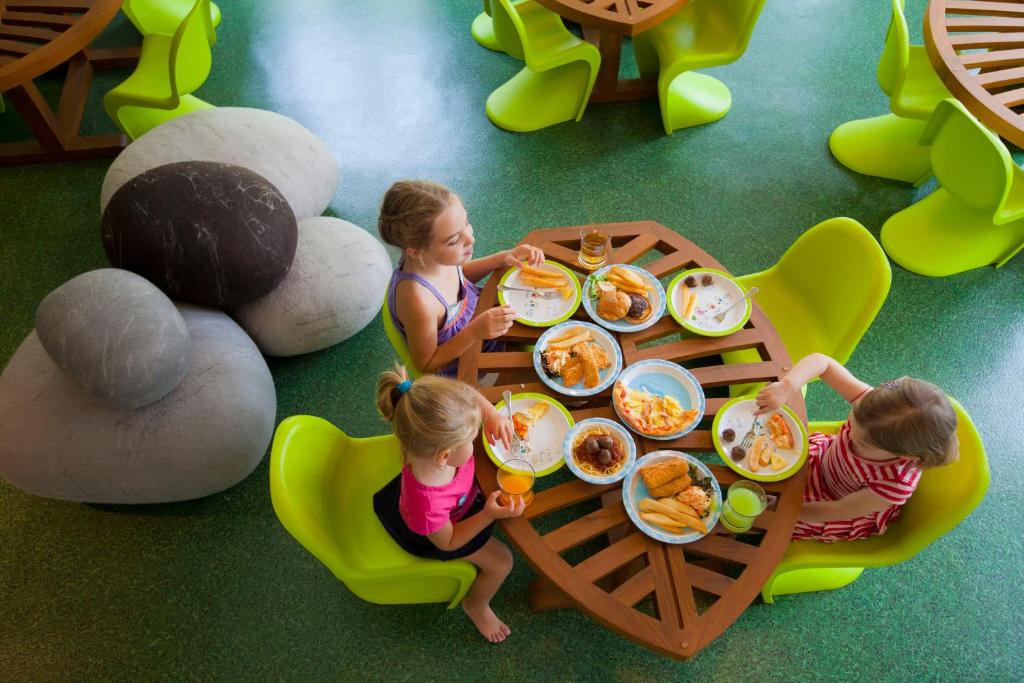 Bērni bauda brokastis Angsana Laguna Phuket, pie galda ar krāsainiem ēdieniem.