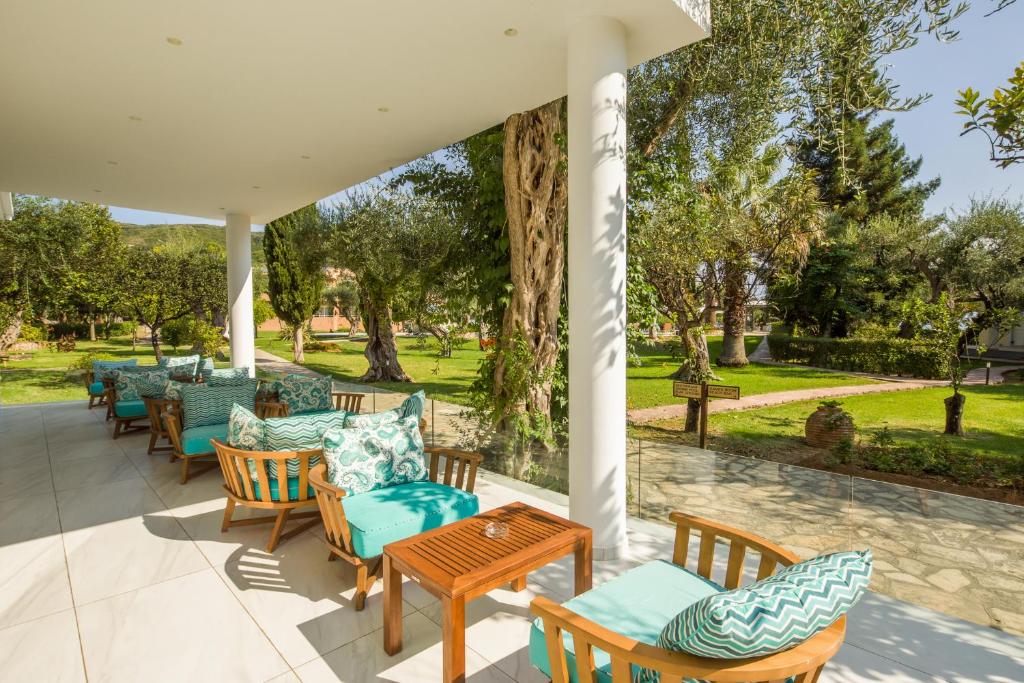 Mūsdienīgs terases skats ar koka mēbelēm un spilveniem, kas atrodas zaļajā dārzā ar augiem un kokiem. Ideāla vieta atpūtai un relaksācijai.