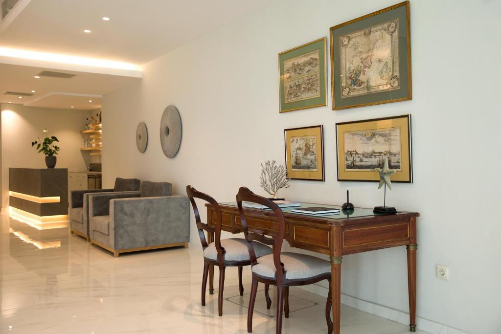 Mūsdienīgs interjers ar elegantu koka galdu un krēsliem, pie sienas izkārtotas mākslas gleznas, gaišas krāsas un stilīga apgaismojuma kombinācija.