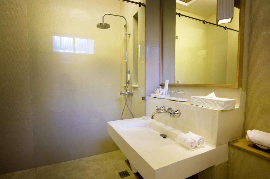 Mūsdienīga vannas istaba ar stikla dušu un elegantu izskatu, kurā ir minimālistiska izlietne un dažādi higiēnas piederumi.