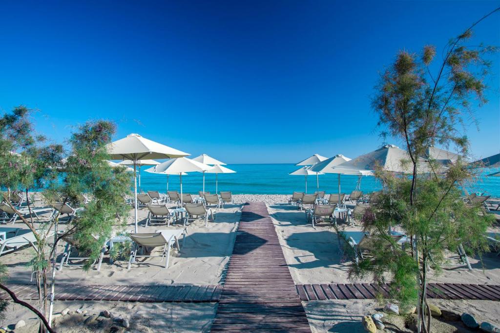 Pludmales skats ar saulessargiem un atpūtas krēsliem, kas vērsti uz skaidro zilo ūdeni un saulainu debesu. Ideāla vieta relaksācijai un atpūtai pie jūras.