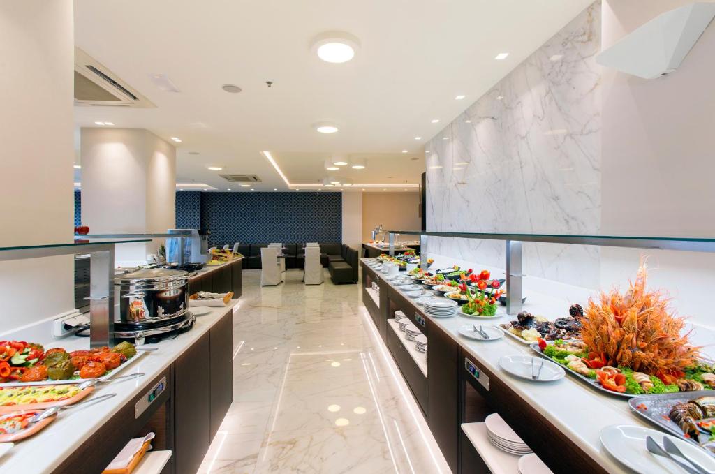 Elegants restorāns ar plašu bufetes izvēli, kurā redzami dažādi ēdieni un salāti, un mūsdienīga interjera dizains. Ideāli piemērots kulinārijas baudījumiem un svinībām.