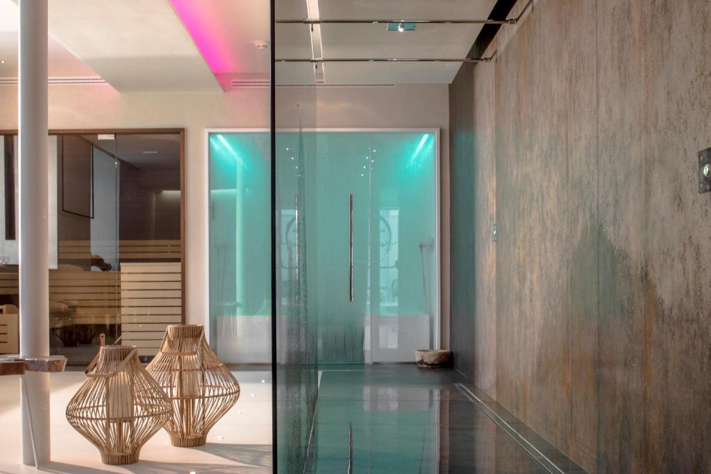 Modernas interjera telpa ar stikla sienām un stilizētām groziem, kas rada elegantu un relaksējošu atmosfēru. Gaisma un krāsainie akcenti piešķir telpai unikālu šarmu.