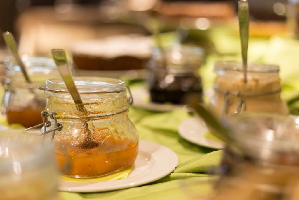 Saldējumā burciņas ar dažādām marmelādēm un mērču, kas sakārtotas uz zaļas galdautas.