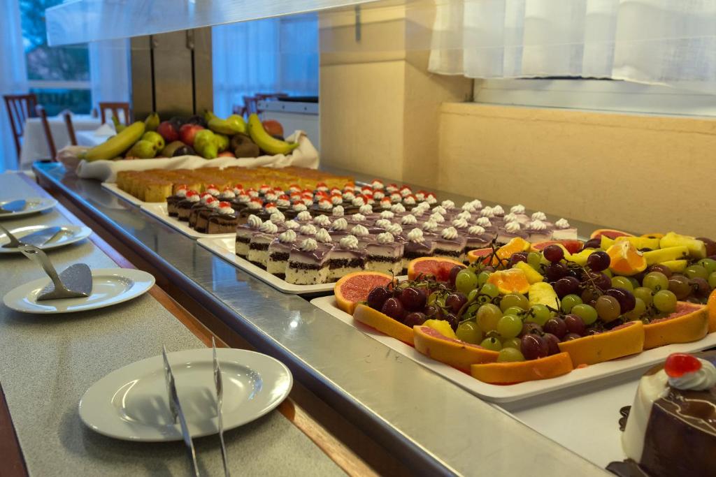 Deserts un augļi uz bufetes galda, ieskaitot kūkas, saldumus un svaigus augļus. Ideāla izvēle saldumu mīļotājiem.