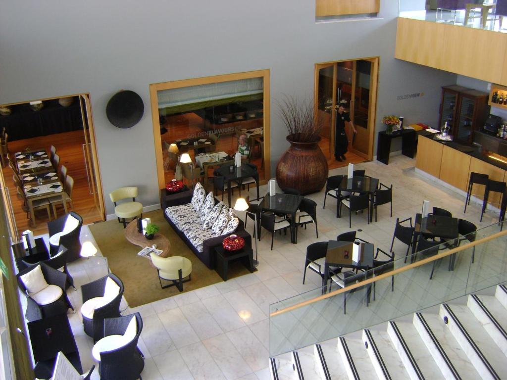 Mūsdienīgs restorāna interjers ar elegantiem galdiem un krēsliem, atvērta telpa, kas aicina viesus uz relaksāciju un ēdienu baudīšanu.