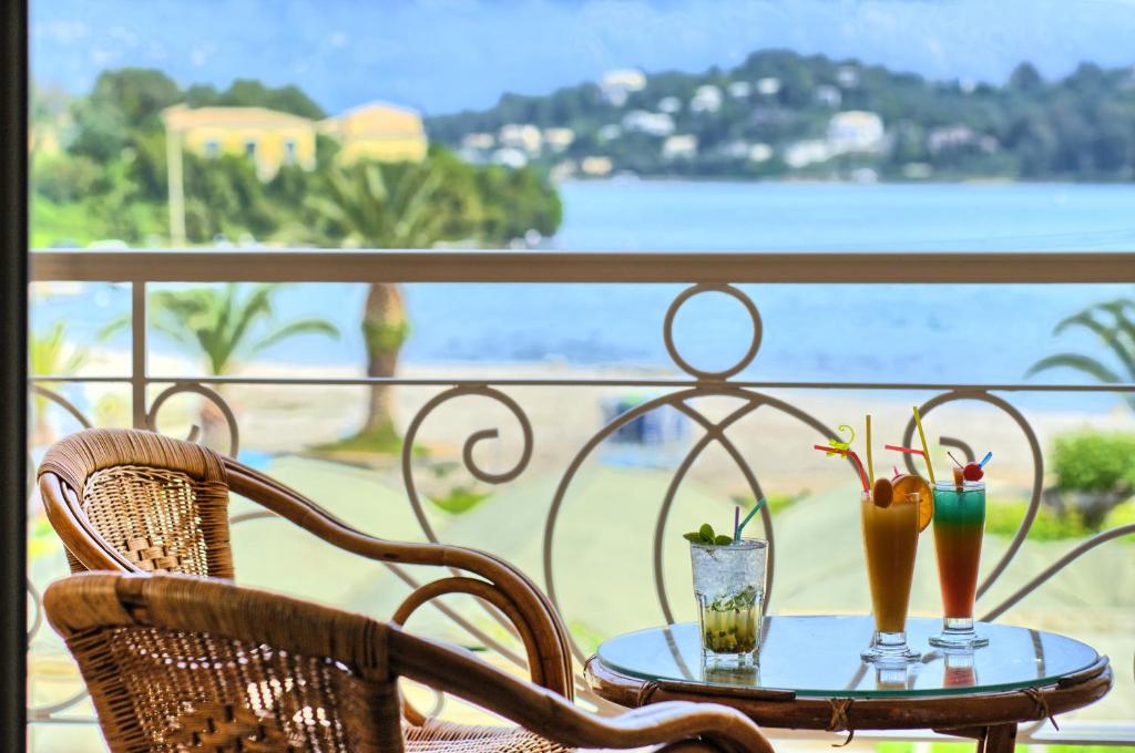 Eksotisku kokteiļu komplekts uz balkona pie jūras, ar palmām un kalnu ainavu fonā. Ideāla vieta relaksācijai un atpūtai.