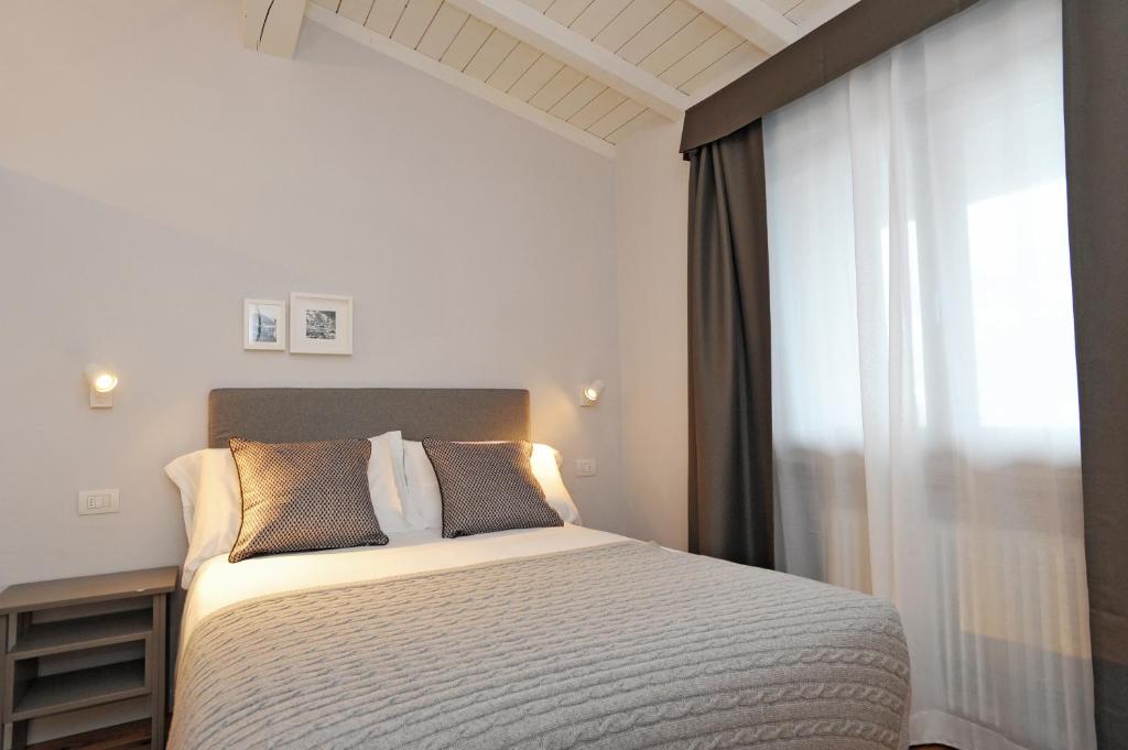 Mūsdienīgi iekārtota guļamistaba ar ērtu gultu, dekoratīvām spilveniem un dabīgu apgaismojumu. Sienās ir gaismas elementi un nelielas fotogrāfijas, kas papildina telpas estētiku.