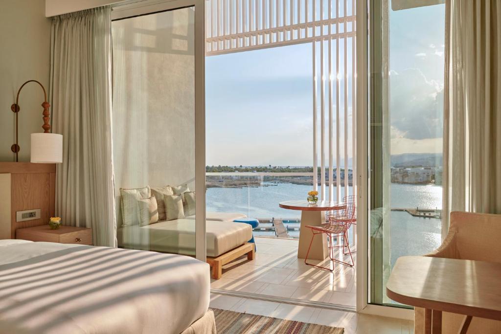 Mūsdienīga viesnīcas istaba ar plašu terasi, no kuras paveras skats uz ūdeni. Interjerā ir gaiši toņi, ērti mēbeļu izkārtojumi un dabīga apgaismojuma elementi.