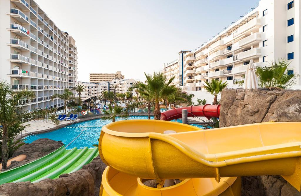 Vasaras atpūtas komplekss ar ūdens slidām un baseinu, apkārt palmām un viesnīcu ēkām. Ideāla vieta ģimenes brīvdienām.