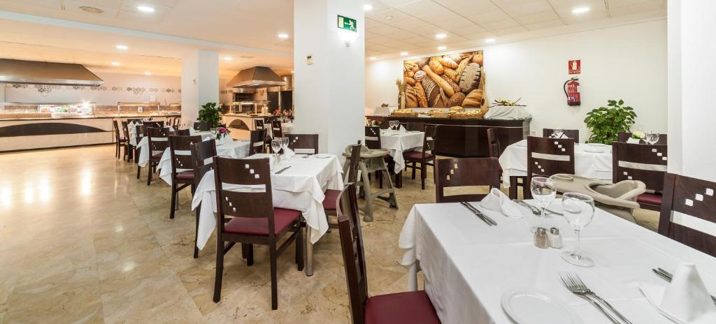 Restorāna interjers ar baltām galdautām, koka galdiem un krēsliem, radot mājīgu atmosfēru. Fons rotāts ar garšīgu maizes attēlu.