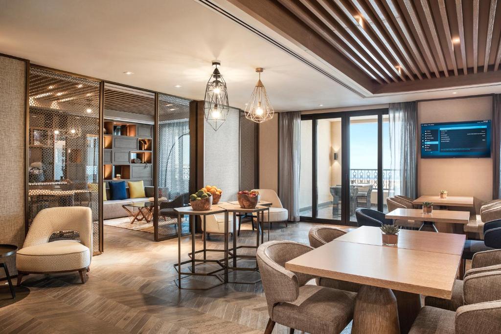 Mūsdienīgs un elegants viesnīcas viesistabas interjers ar stilīgiem mēbelēm un plašiem logiem, kas nodrošina dabiska apgaismojuma plūsmu. Komfortabli sēdvietas un dekoratīvi elementi rada siltu un viesmīlīgu atmosfēru.