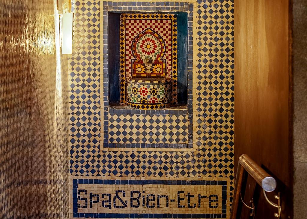 Mūsdienīgs spa interjers ar mozaīkas apdari, kas ietver krāsainus elementus un iekārtu ar uzrakstu "Spa & Bien-Etre".